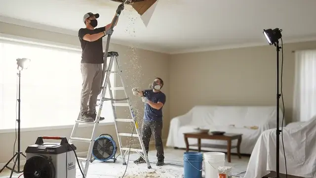Water-damaged ceiling being repaired by a restoration professional